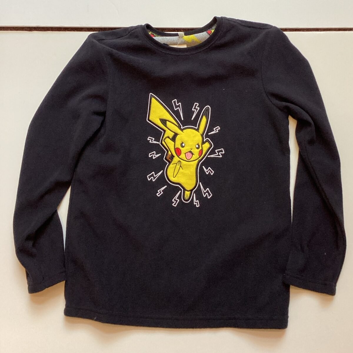 Step up your style game with this cozy Pokémon Black fleece top from the Random Box 2 collection. Perfect for fans of the iconic franchise, this top is a must-have addition to your wardrobe. Add it to your cart now and embrace the Pokémon trainer vibes!