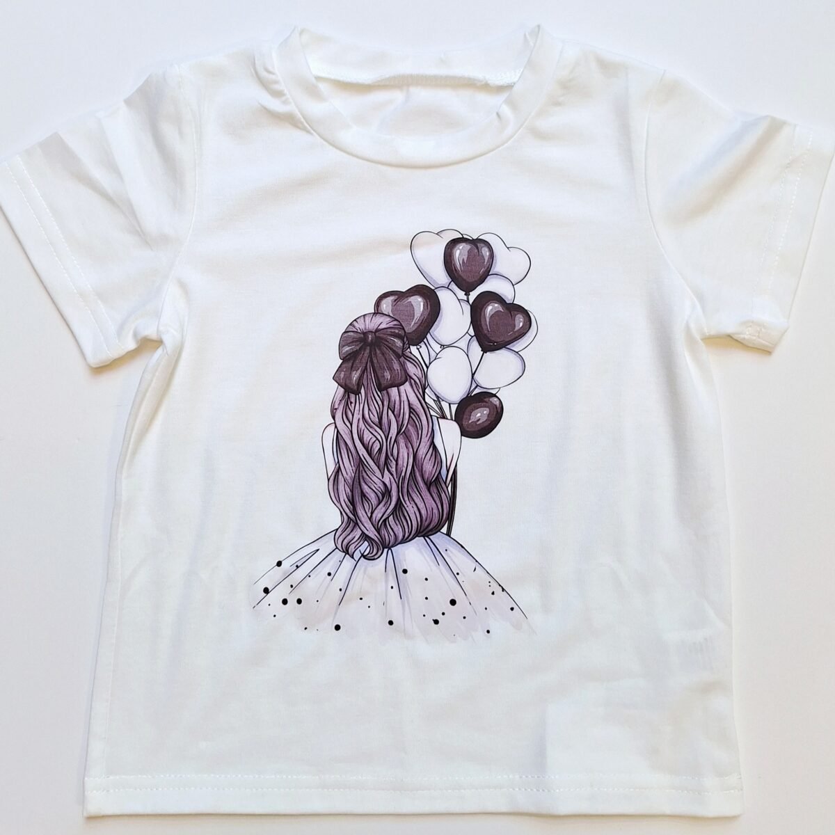 Elevate your little one's wardrobe with this adorable Girls White T-Shirt featuring a charming Purple Girl and Balloons design. Crafted from high-quality material, this versatile style is perfect for any occasion. Add it to your cart now!