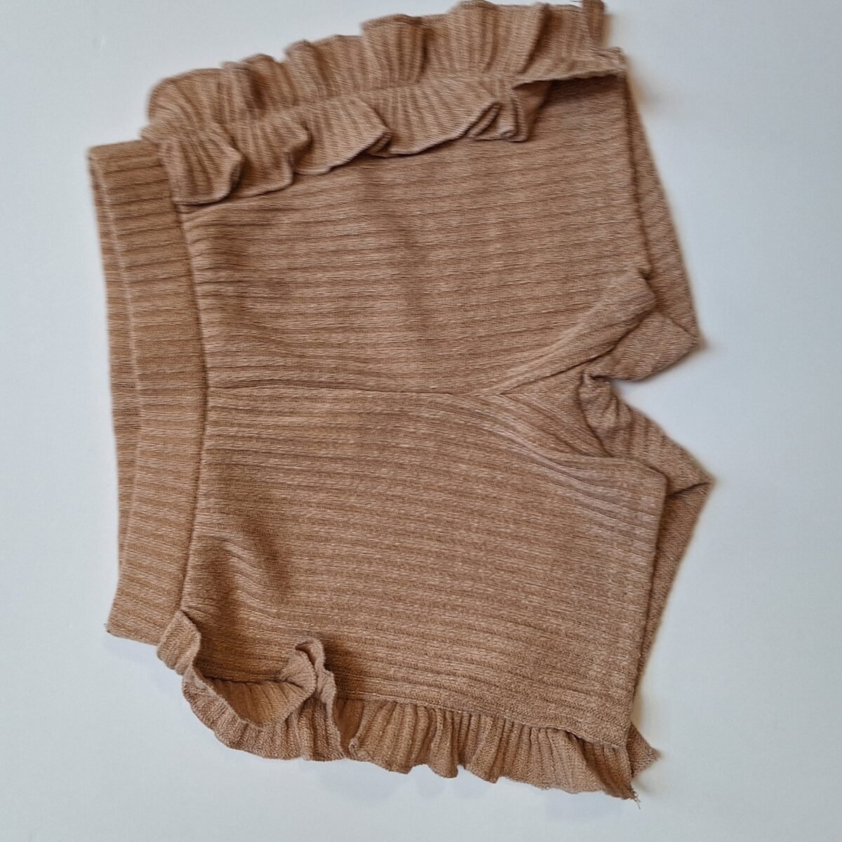 Elevate your summer style with these chic light brown ribbed shorts featuring adorable frilly sides. A must-have for a trendy and playful look!