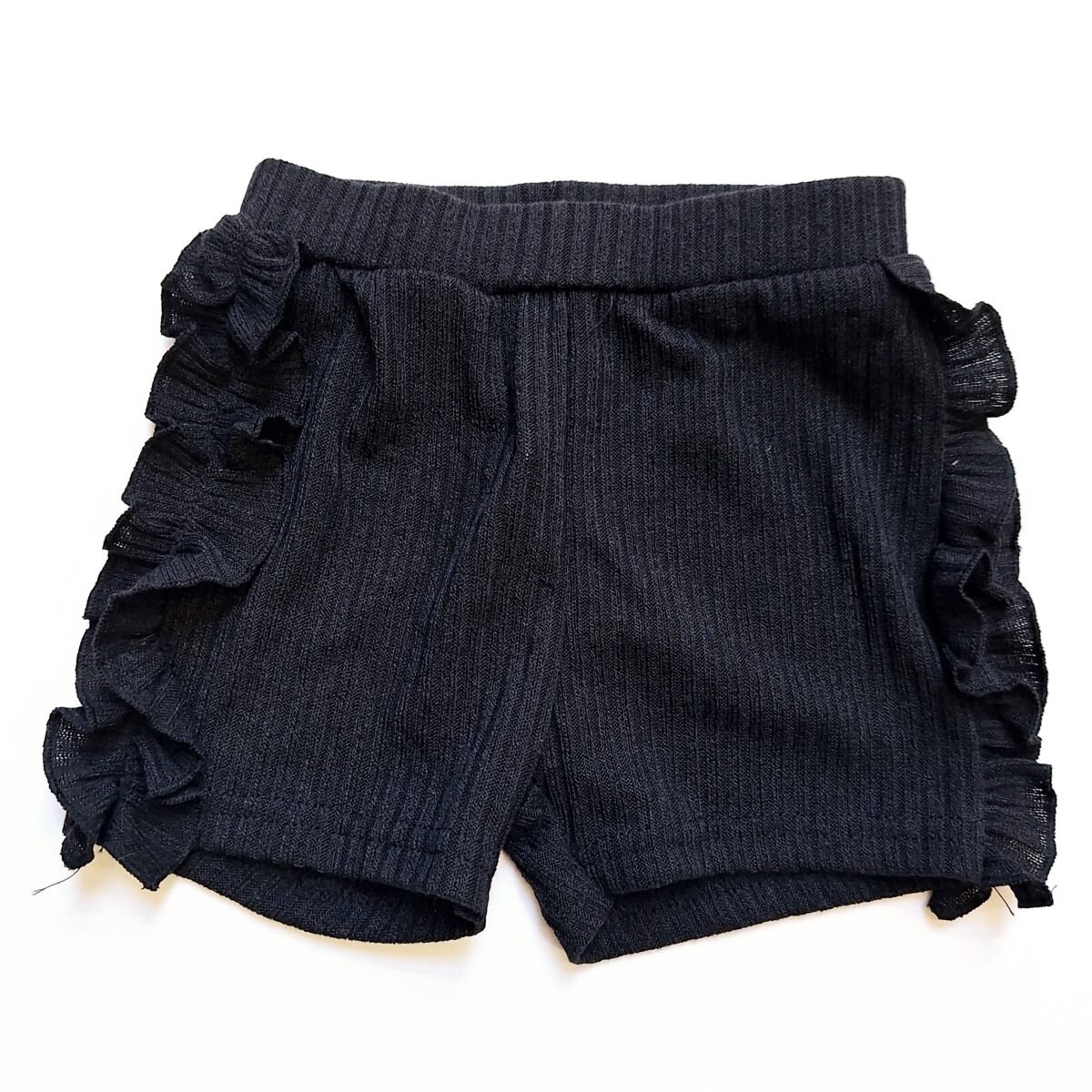 Elevate your summer style with these black ribbed shorts featuring adorable frilly sides. A must-have for a trendy and playful look!