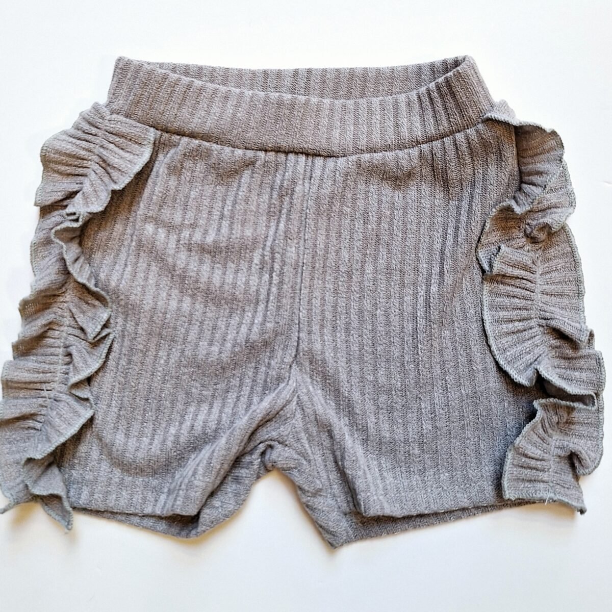 Elevate your summer style with these grey ribbed shorts featuring adorable frilly sides. A must-have for a trendy and playful look!