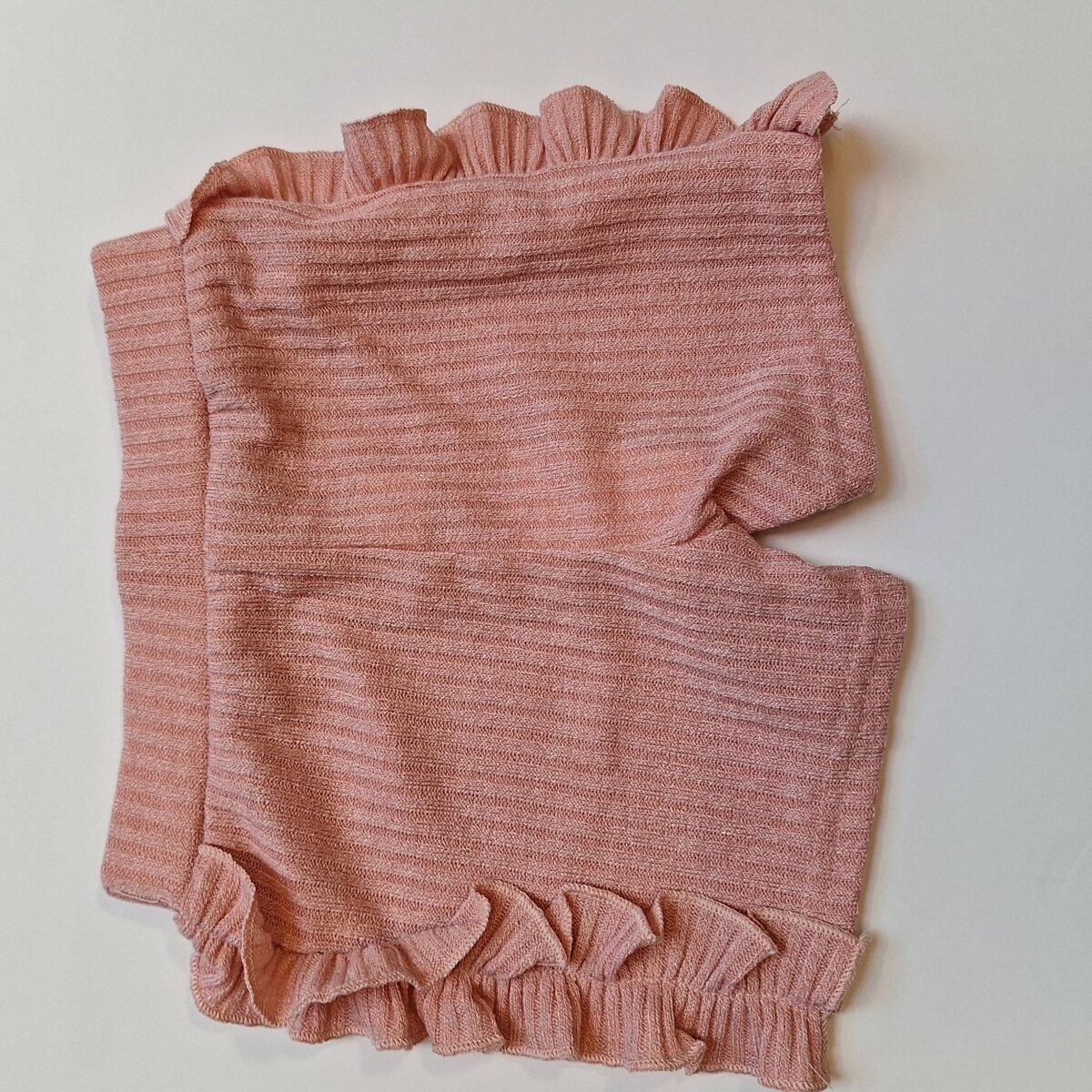 Elevate your summer style with these light pink ribbed shorts featuring adorable frilly sides. A must-have for a trendy and playful look!